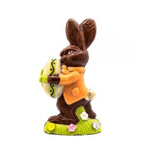 chocolate bunny in an orange jackets holding a yellow easter egg